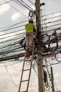 CHIANG MAI, THAILAND - 17 Mayıs 2020: Güvenli kıyafetler giyen işçiler Chiang Mai, Tayland 'daki elektrik direkleriyle internete bağlanmak için kablolar kuruyorlar