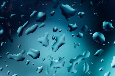 Cam yüzeyindeki su damlacıklarının çok renkli arkaplanı yansıtan soyut görüntüsü.