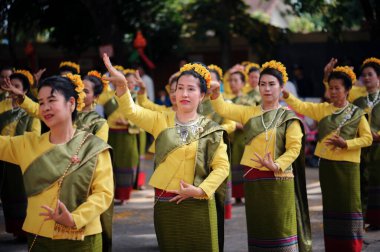 CHIANG MAI, THAILAND - 11 Kasım 2018: Geleneksel erdem festivalinde sarı kumaş giymiş Asyalı kadınlar dans ediyor. Chiang Mai, Tayland 'da