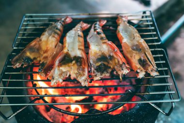 Büyük karidesler demir bir ızgaraya konur ve sıcak kömür sobasının üzerinde kızartılır..