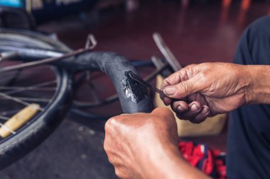 Tamirci bisikletin iç tüpünü yapıştırıcı ve yamayla onardı..