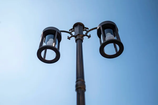 Lamps mounted to outdoor poles on blue background.