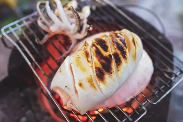 Grilled squid on a cast iron grill over a charcoal grill.