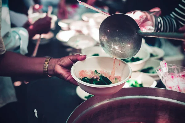 Volunteers handing delicious food to the homeless poor : concept of hunger problem