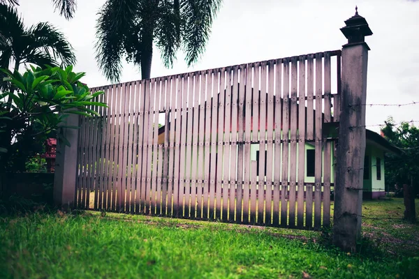 The dilapidated gate of the house made of white timber was closed to prevent intrusion.