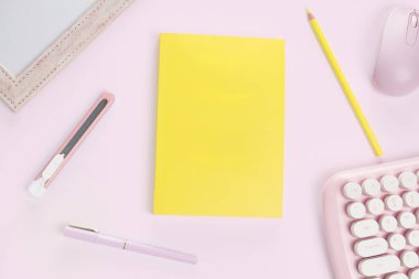 düz sarı renkli kitap ve kırtasiye malzemesi mor pastel zeminde.