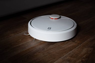 Yerde beyaz robot elektrik süpürgesi var..
