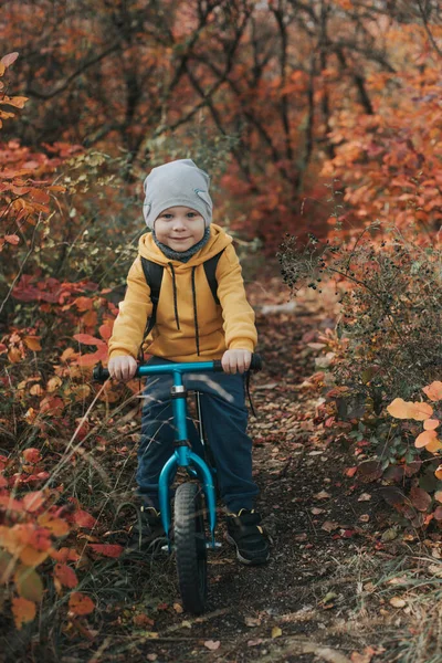 Boy on a balance bike ride in the autumn forest — Stock Photo, Image