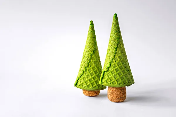 Waffle külahından yapılmış iki Noel ağacı ve beyaz arka planda şampanya mantarları. Uzayı kopyala Noel ağacı olarak dondurma külahlı yaratıcı bir kavram..