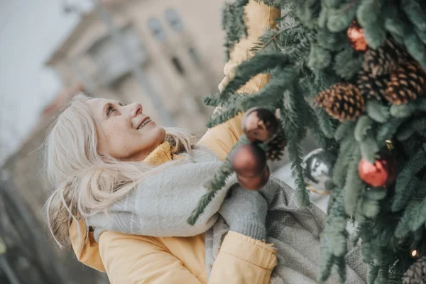 Старая красивая женщина с светлыми волосами на площади среди рождественских елок. — стоковое фото