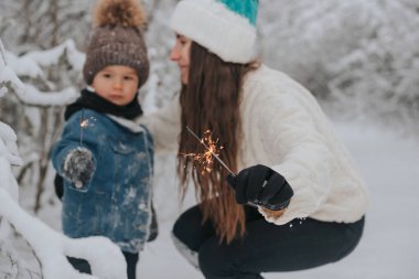 Anne ve oğlu karda yürüyorlar ve ormanda kıvılcım saçıyorlar..