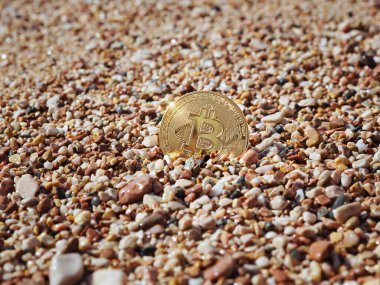 Kumlu deniz kıyısındaki bitcoin. Serbest para, kripto para kavramı