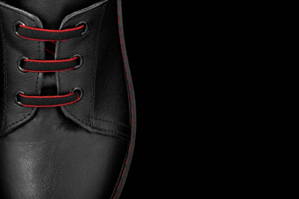 Black oxford shoe on a black background.