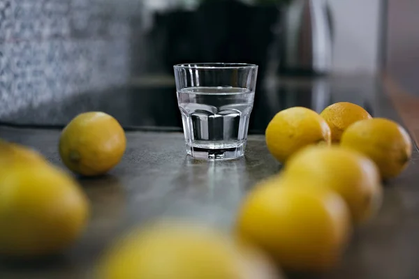 Ett glas vatten och en massa citroner på bänkskivan.. — Stockfoto