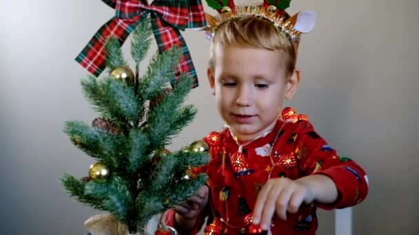 Mutlu çocuk Noel ağacını toplarla süslüyor. Boynuzlu çocuk ağacı süslüyor. — Stok video