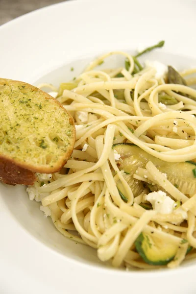 Linguine con formaggio feta, zucchine e pane all'aglio — Foto Stock