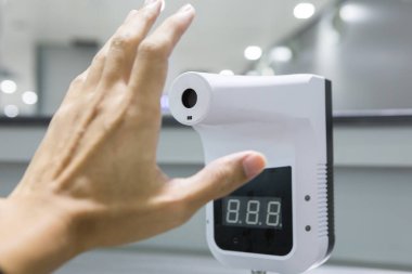 Bulanık arkaplanda kızılötesi termometre. İnsanlar binaya girmeden ya da herhangi bir hizmet kullanmadan önce sıcaklıklarını ölçmek zorundalar. Corona virüsü ve covid 19 konsepti.