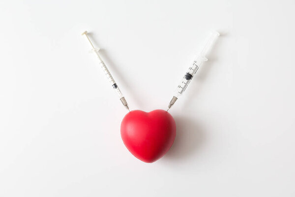 Heart was stabbed by a syringe on white background and copy space for health care concept