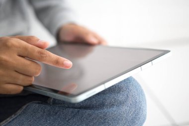 Gri gömlekli, el ele tutuşan ve tablet kullanan bir kadın. Kadın sosyal medya konsepti hakkında konuşuyor.