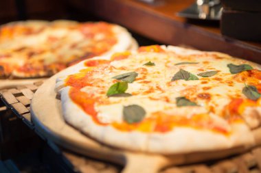 Açık büfedeki ahşap tepside pizzanın seçici odak noktası.