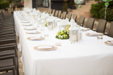 Düğünde uzun bir yemek masası. Açık hava düğününde masa örtüleriyle süslemeler..