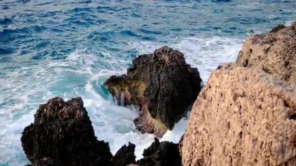 Волны моря или океана разбиваются о скалы. вид гор, торчащих из-под воды, вода шлифует большие валуны и камни. — стоковое видео
