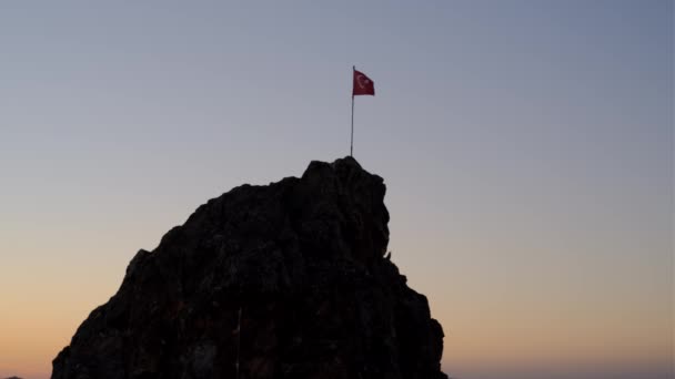Turkiets flagga utvecklas mot bakgrund av fallande himmel, solen har redan satt över horisonten. ensam och stolt röd flagga med symboler för Turkiet står på berget. — Stockvideo