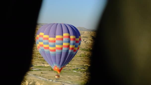 Gyönyörű kilátás nyílik a nagy hőlégballon napkeltekor háttér a város magasból és más léggömbök. többszínű ballon által vezérelt aeronauta legyek felett mező. — Stock videók