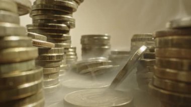 Sarı metal paraların içinden ağır çekiç, 10 Rus rublesi. Masada yığınla bozuk para var, makrofondip. Kamera geri gidiyor, bozuk paraların etrafında duman var. İnsanların tasarrufu, finansal bağımsızlık