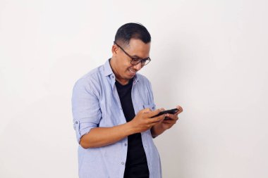 Stüdyoda beyaz arka planda mobil oyun oynamaya bağımlı Asyalı adam eğlencesi.