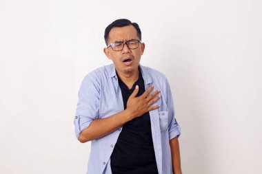 Asyalı adam acı çekiyor ve elini göğsüne dokunmak için kullanıyor. Kalp krizi belirtilerini kontrol etmek için. Akıl sağlığı konsepti.