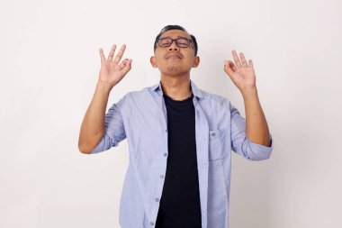 Günlük kıyafet giyen Asyalı adam meditasyon yoga yapıyor beyaz arka planda izole edilmiş bir poz, meditasyon konsepti.