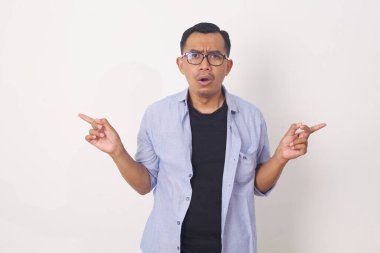 Kararsız, kafası karışmış Asyalı bir adamın portresi. Şov yolunu gösteriyor, sağa sola işaret ediyor, hangi varyantı seçtiğini soruyor.