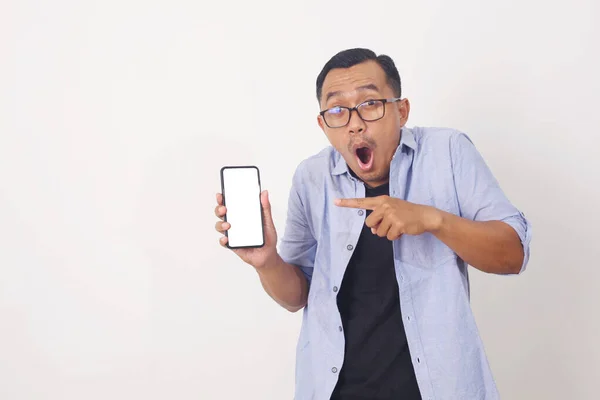 一个快乐的亚洲男人站着 拿着手机指指点点的画像 与白种人隔离 — 图库照片