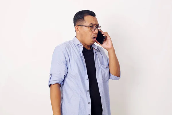 携帯電話で話している間 カジュアルな表情でアジア人男性はショックを受けました 白い背景を背景にしたハーフボディのスタジオショット — ストック写真