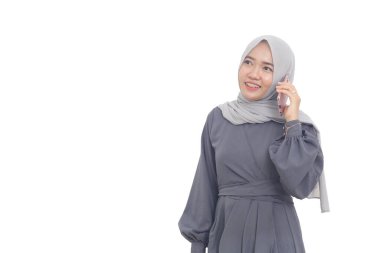 Mutlu Asyalı Müslüman kadın telefonda dikilip bir şeyler arıyor.