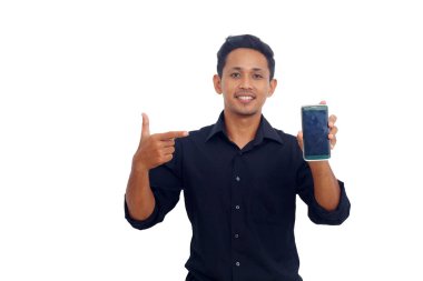 Gülümseyen Asyalı bir adamın portresi beyaz arka plandaki boş ekran cep telefonunu işaret ediyor.