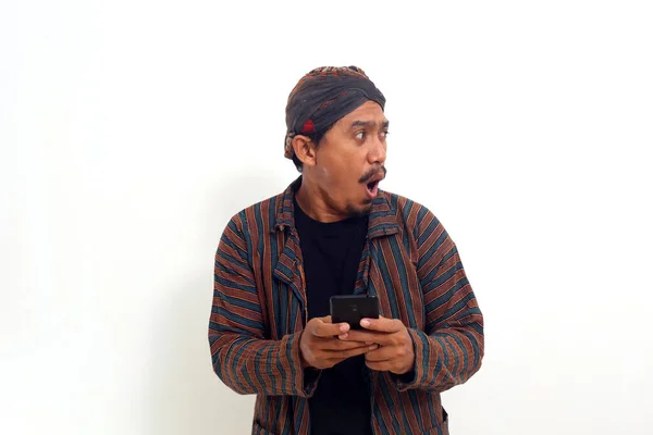 Surpreendido Asiático Homem Enquanto Segurando Telefone Celular Olhando Lado Dele — Fotografia de Stock