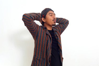 Geleneksel kostümlü Asyalı adam elleri başının arkasında durup mutlu bir şekilde ıslık çalıyor.