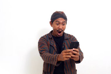 Başarılı bir Asyalı cep telefonu tutarken ayakta duruyor ve iyi haberler alıyor. Beyazda izole edilmiş