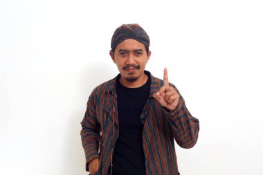 Geleneksel java kostümlü Asyalı adam parmağını gösterirken ayakta duruyor. Beyaz arkaplanda izole