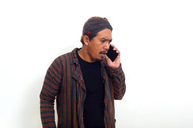 Geleneksel jakuzi kostümlü kızgın Asyalı adam telefonundan haber okurken ayakta duruyor..