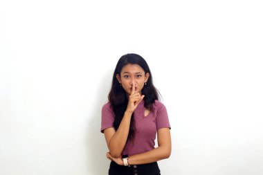 Güzel Asyalı kız dudaklarını parmaklıyor sessiz sessiz bir jest. Beyaz arkaplanda izole