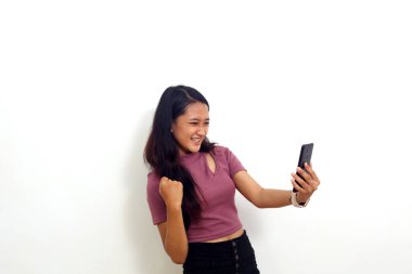Mutlu Asyalı genç kız ayakta dururken cep telefonundan iyi haberler alıyor. Beyazda izole edilmiş