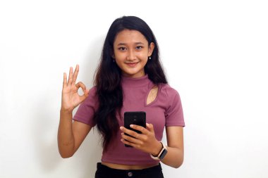 Güzel kız cep telefonunu tutarken beyaz arka planda izole edilmiş iyi bir hareket göster.