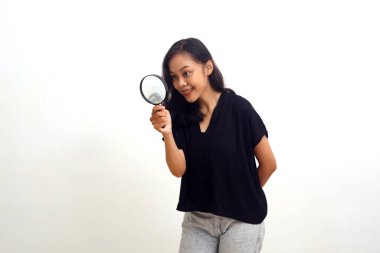 Asyalı genç bir kadın büyüteçten bakarken ayakta duruyor. Beyazda izole edilmiş