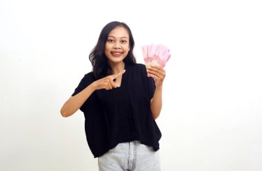 Asyalı genç bir kadın elinde Endonezya parası tutarken ayakta duruyor. Beyazda izole edilmiş