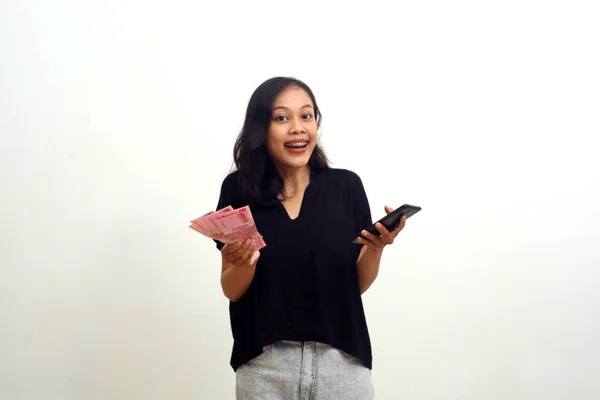 Glückliche Asiatische Junge Frau Mit Indonesischem Geld Und Handy Isoliert — Stockfoto