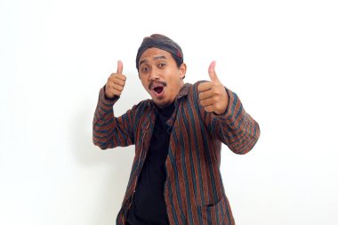 Heyecan verici Asyalı adam ayakta ve iki eliyle baş parmağını kaldırıyor. Beyaz arkaplanda izole