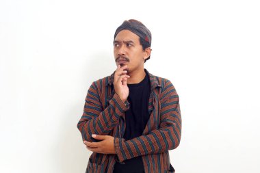 Yan bakarken düşünceli Asyalı adam ayakta duruyor. Beyaz arkaplanda izole